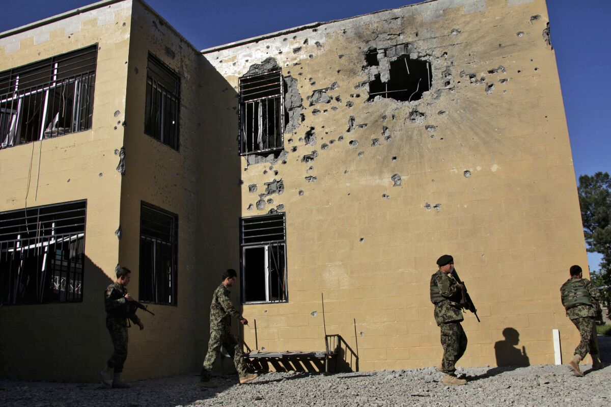 Afghan soldiers patrol outside the destroyed courthouse in Farah, in western Afghanistan. The Taliban has declared courthouses and their personnel targets.