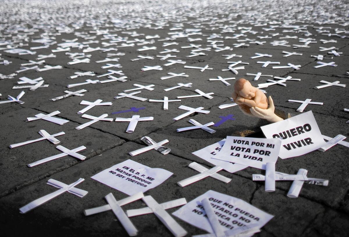 A doll cradled in hands lies among crosses covering Mexico City's Zocalo square during a 2008 protest against the legalization of abortion.