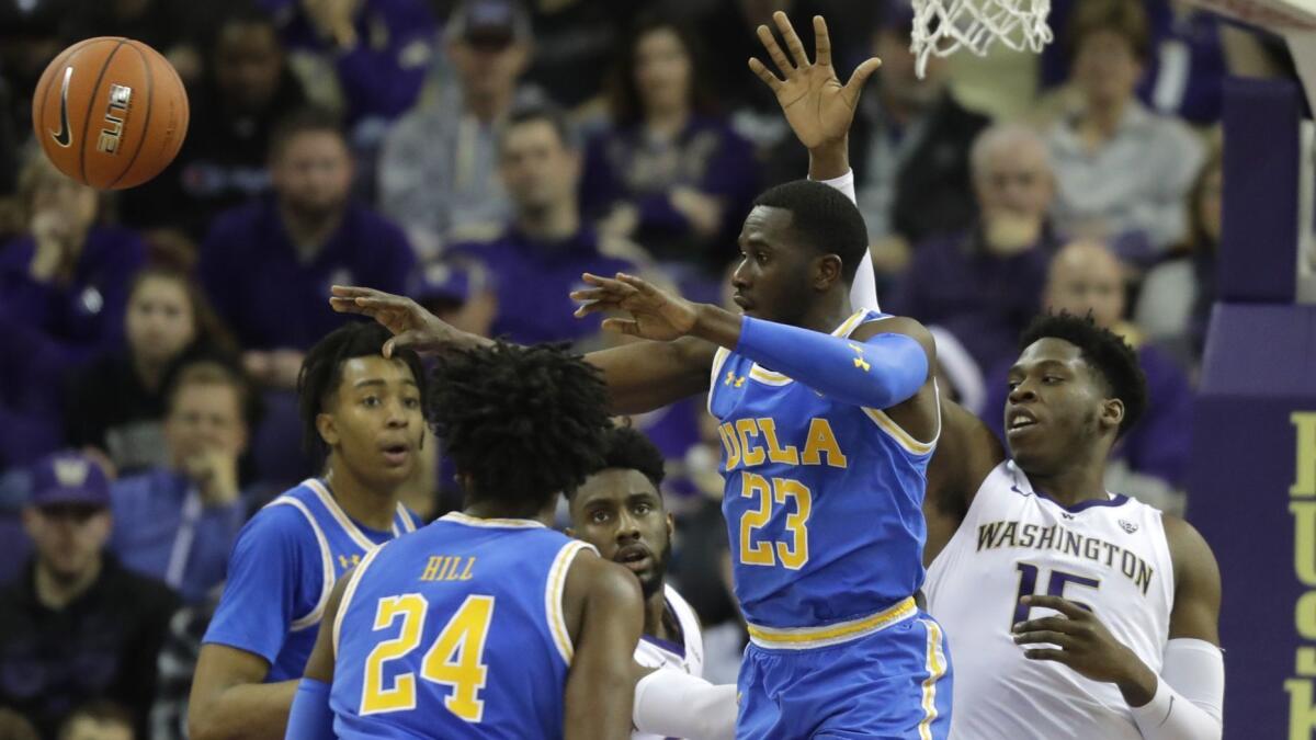 UCLA guard Prince Ali passes under pressure from Washington forward Noah Dickerson during the first half.