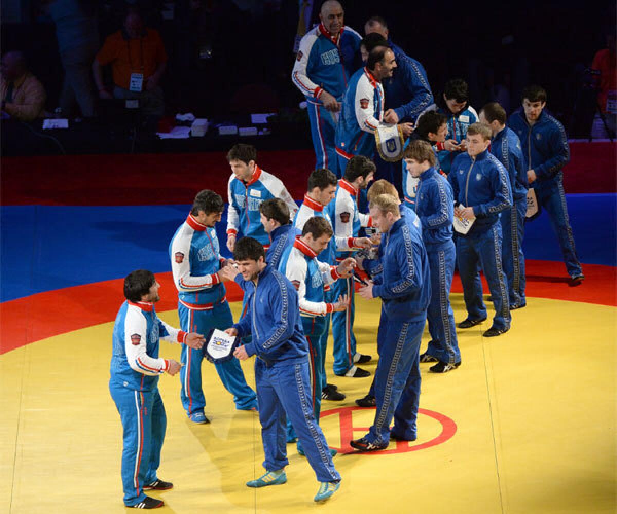 Team Russia and Team Ukraine wrestlers greet and exchange gifts before competition during the 2014 FILA Freestyle World Cup at The Forum on Saturday.