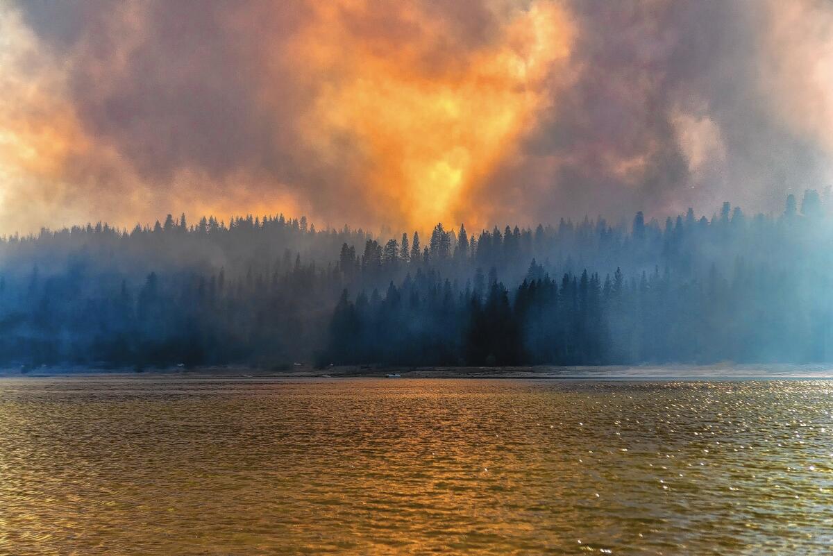 A photo provided by YosemiteLandscapes.com shows smoke rising Sunday from a wildfire burning near Bass Lake.