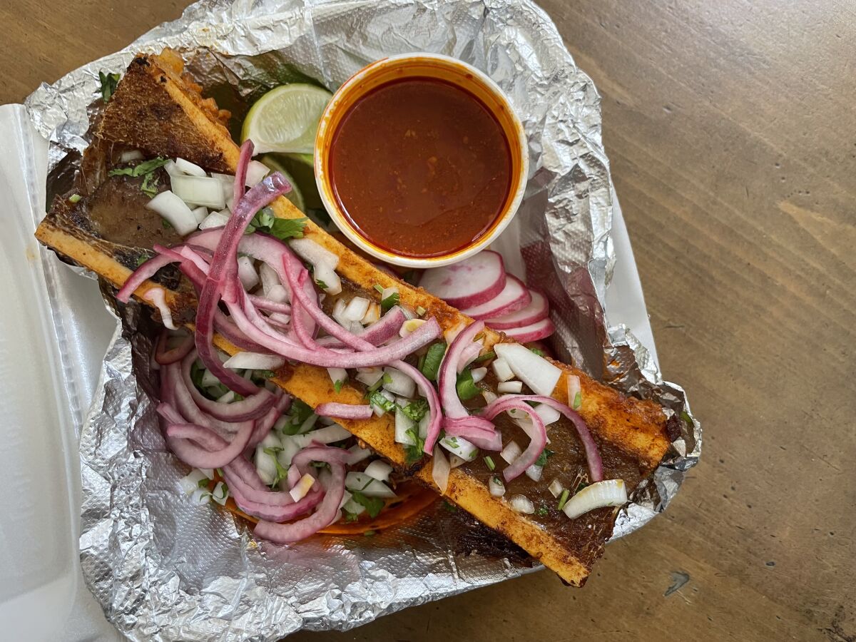 Sliced red onions top a bone marrow taco.