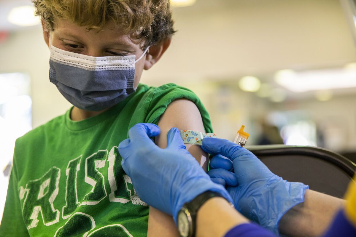 A boy gets a bandage on his arm after receiving a shot