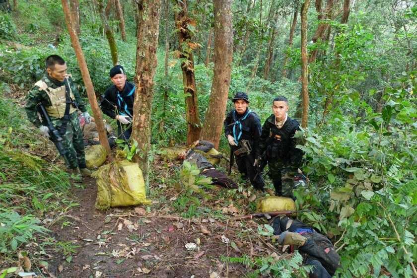 Thailand soldiers stand with seized packages of illegal drugs and the body of a suspected smuggler at the scene of a gunfire exchange a day earlier in the Fang district in Chiang Mai, northern Thailand, Thursday, Dec. 8, 2022. Thai soldiers clashed with suspected drug smugglers in a forested area in the country's north near the Myanmar border, killing 15, authorities said Thursday. (Pha Muang Force via AP)