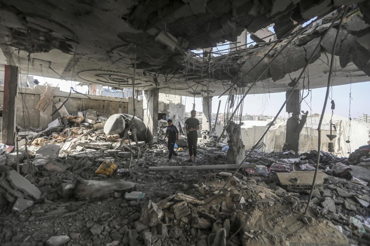 People stand in the rubble of a ruined home.