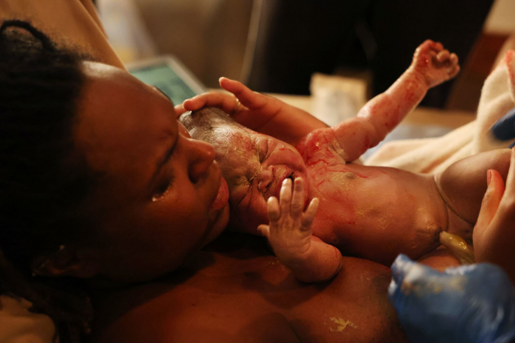 A woman holds her baby moments after delivery