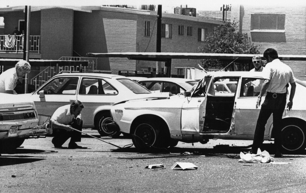 People examine a car damaged in a bomb explosion.