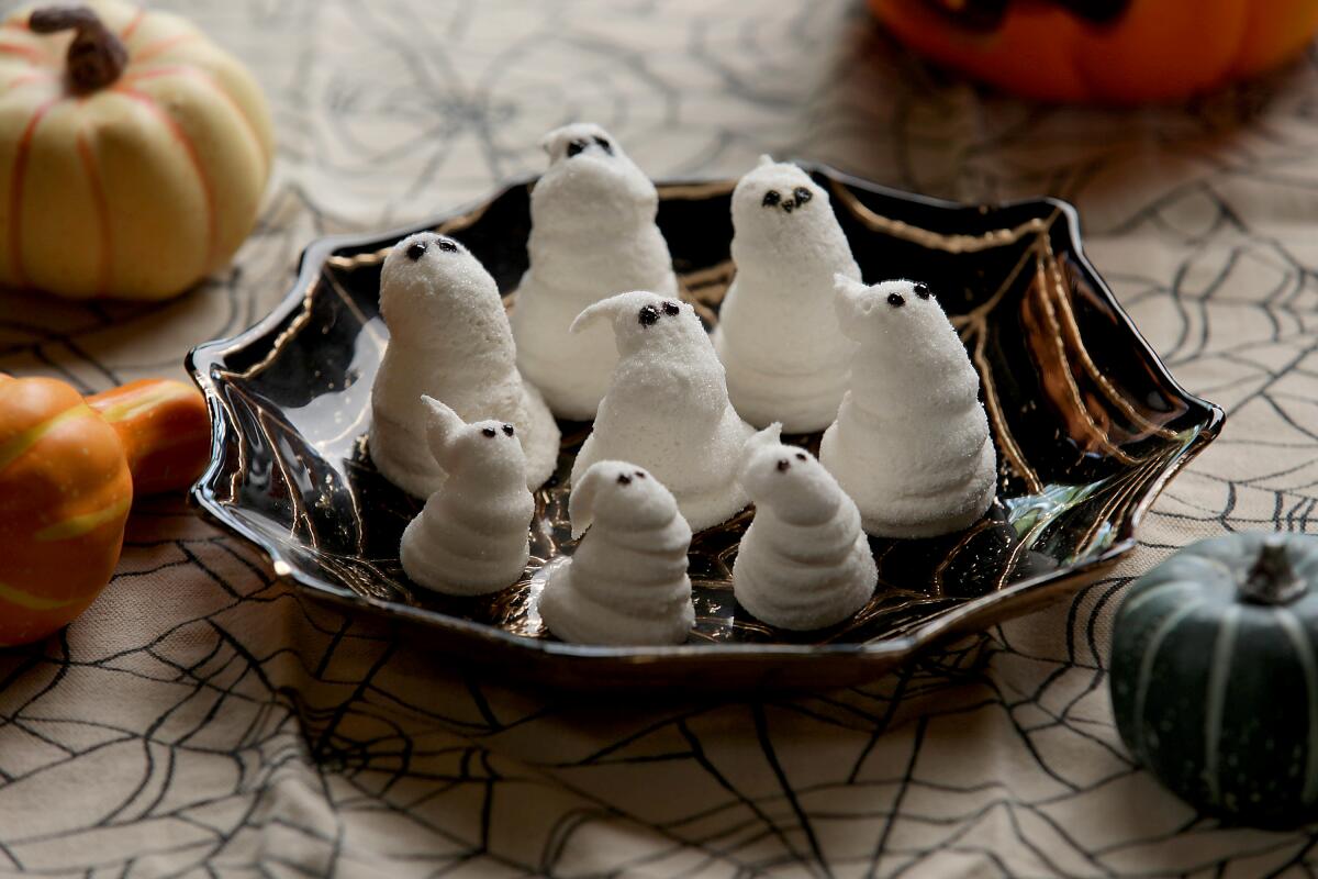 Homemade ghost-shaped marshmallow candies in a spiderweb ceramic tray