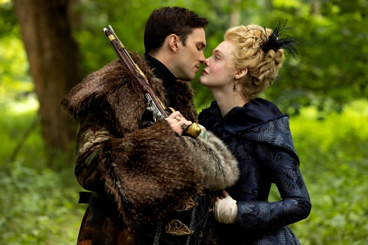 A man in a fur coat and holding a gun leans in to kiss a woman in a scene from "The Great."