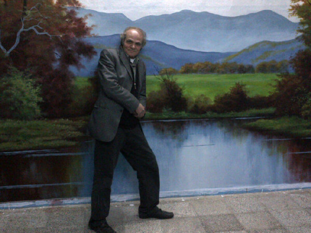 Syrian artist Nader Haj Kadour completed three murals in less than a month at a vocational high school in the Turkish border town of Reyhanli, including this landscape. The artist poses here with his work.