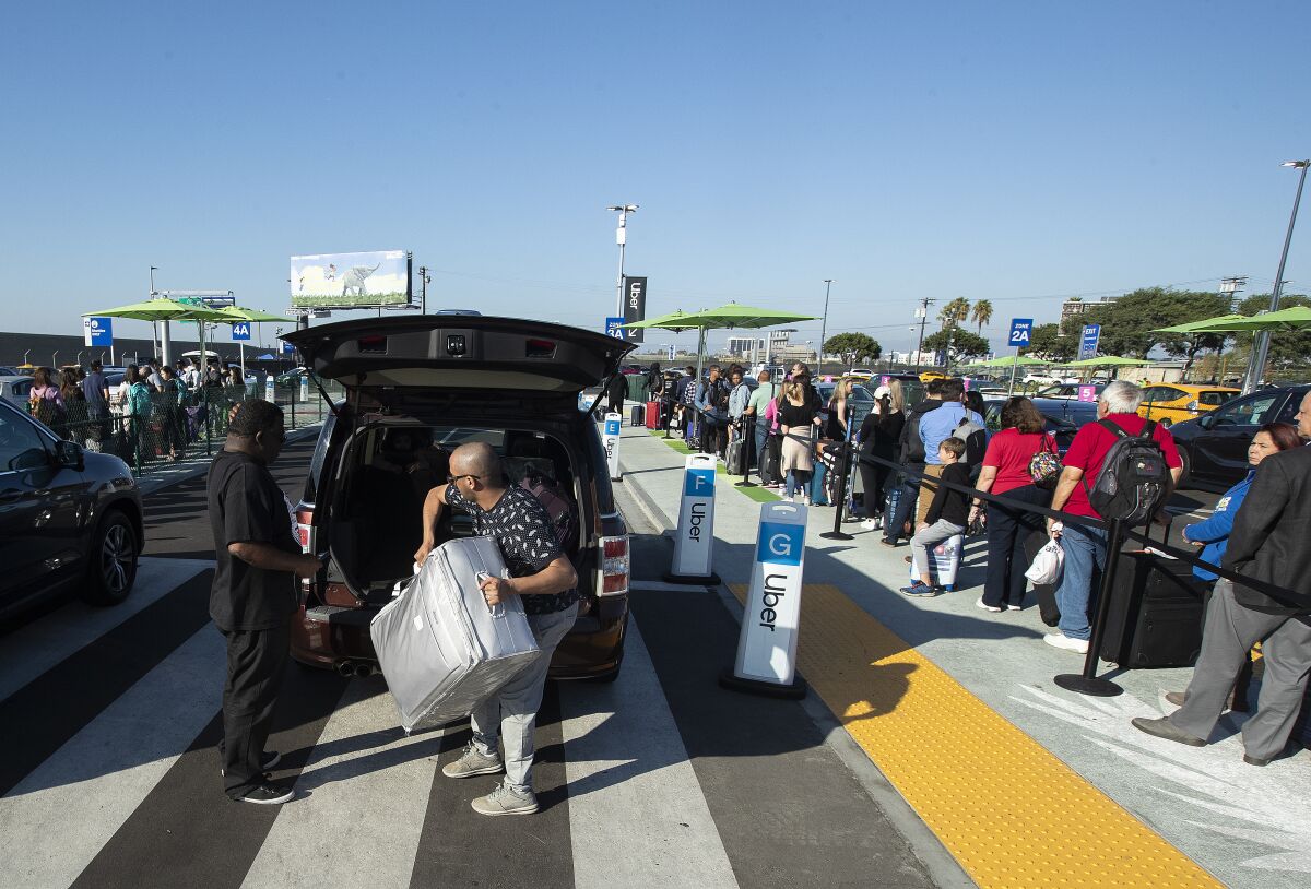 Long lines form as people wait to catch a ride with Uber in a pickup area called "LAXit" at Los Angeles International Airport on Monday.