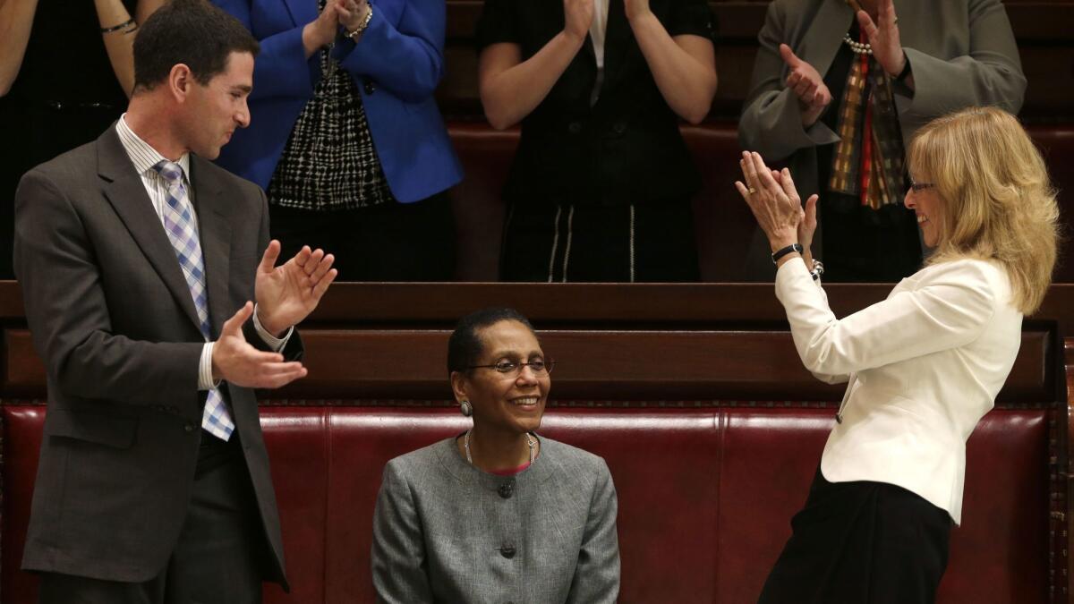FILE- In this May 6, 2013 file photo, Justice Sheila Abdus-Salaam, center, receives applause after her confirmation to serve on the New York State Court of Appeals from Craig Alfred of Gov. Andrew Cuomo's appointments office, left, and Albany City Court Judge Rachel Kretser, in the Senate gallery at the Capitol in Albany, N.Y. New York City Police confirmed that Abdus-Salaam's lifeless body was found on the shore of the Hudson River off Manhattan on Wednesday, April 12, 2017. (AP Photo/Mike Groll, File)