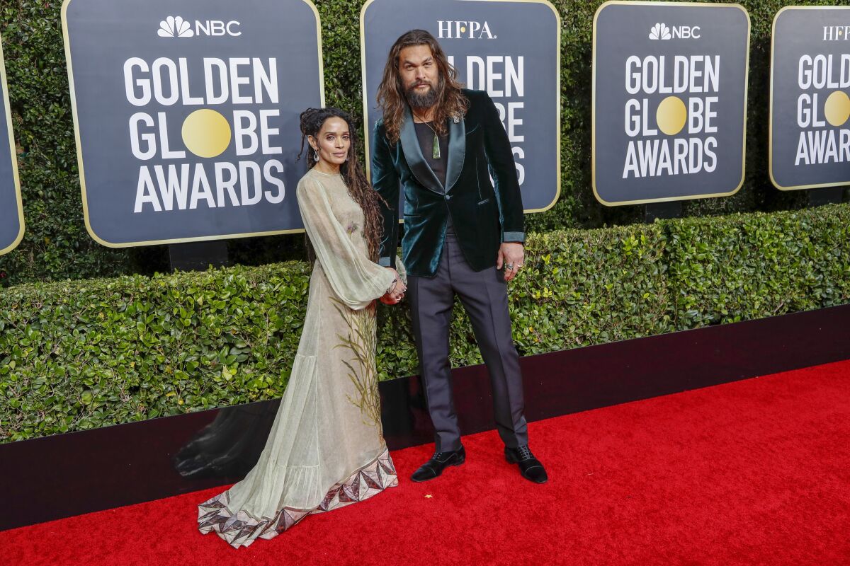 A woman and a man pose in formal attire on a red carpet