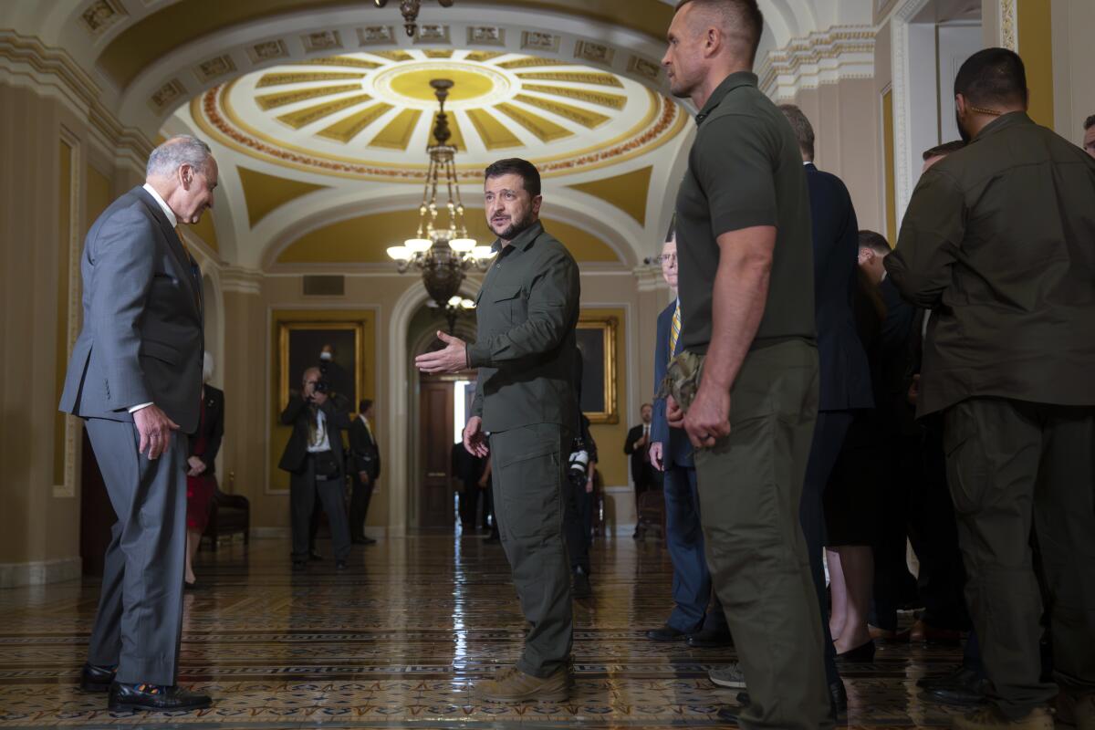 Senate Majority Leader Charles E. Schumer talks with Ukrainian President Volodymyr Zelensky in an ornate hall.