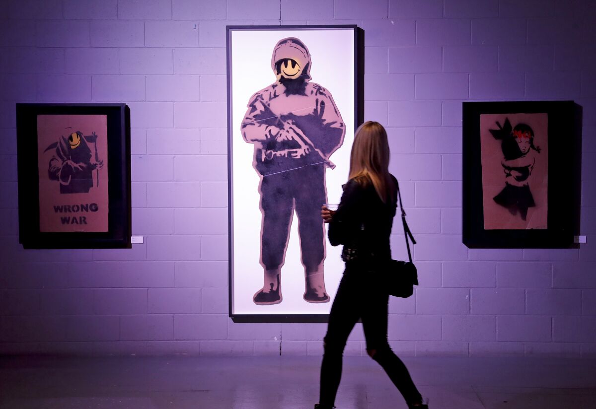 Guests walk by "Smiling Copper" at the "Banksyland" exhibit.