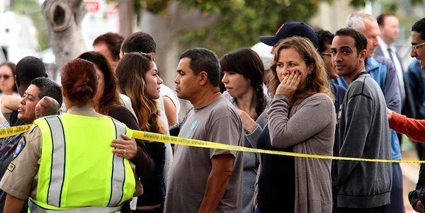 Students and faculty members gather along 17th Street after being evacuated from Santa Monica College.