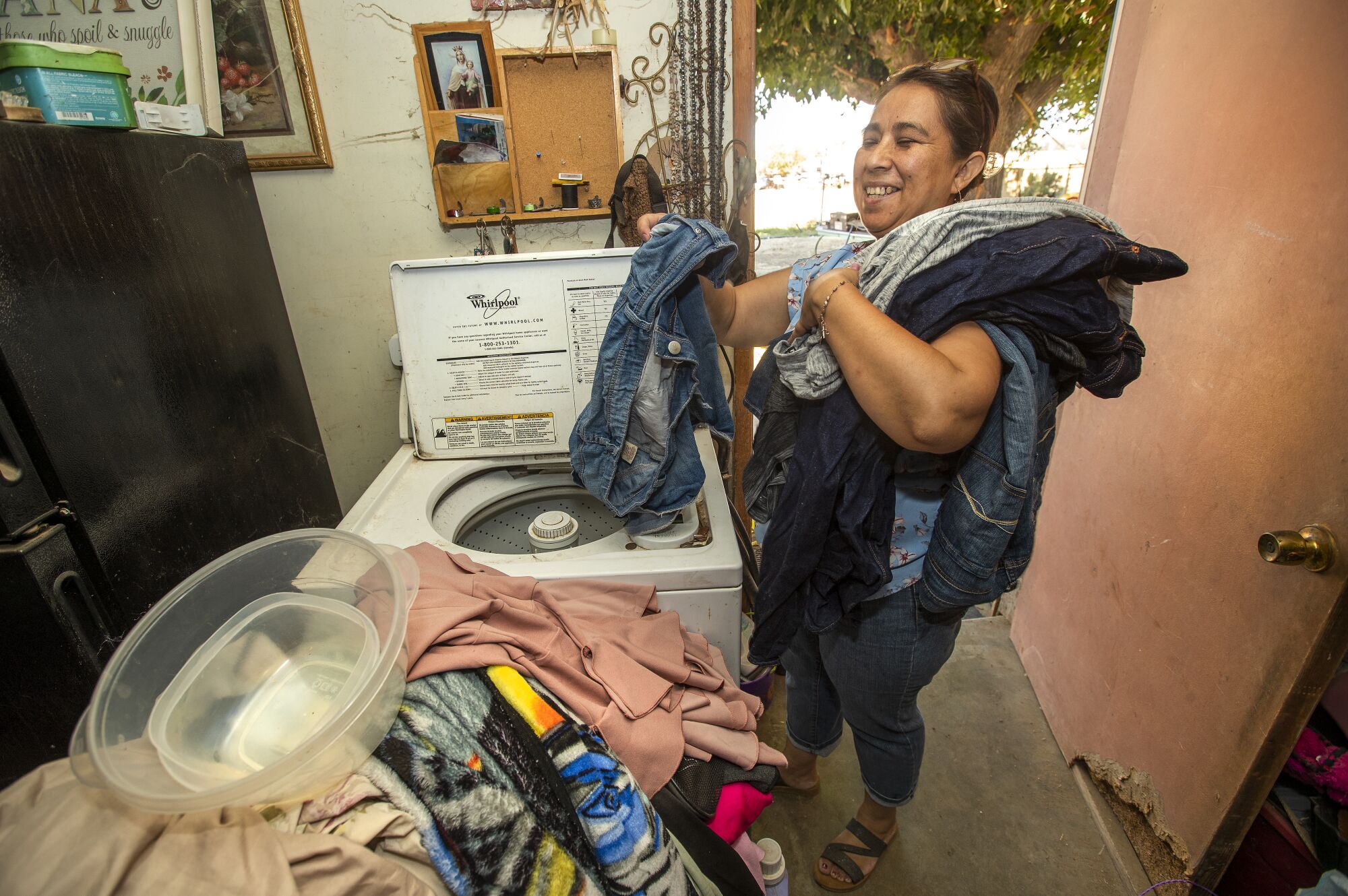 A woman removes clothing from a washing machine
