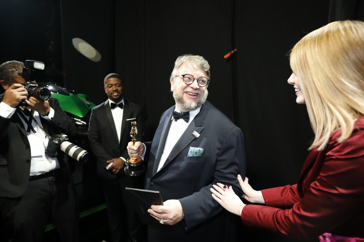 Guillermo del Toro after winning the Oscar for directing, with presenter Emma Stone backstage at the 90th Academy Awards.