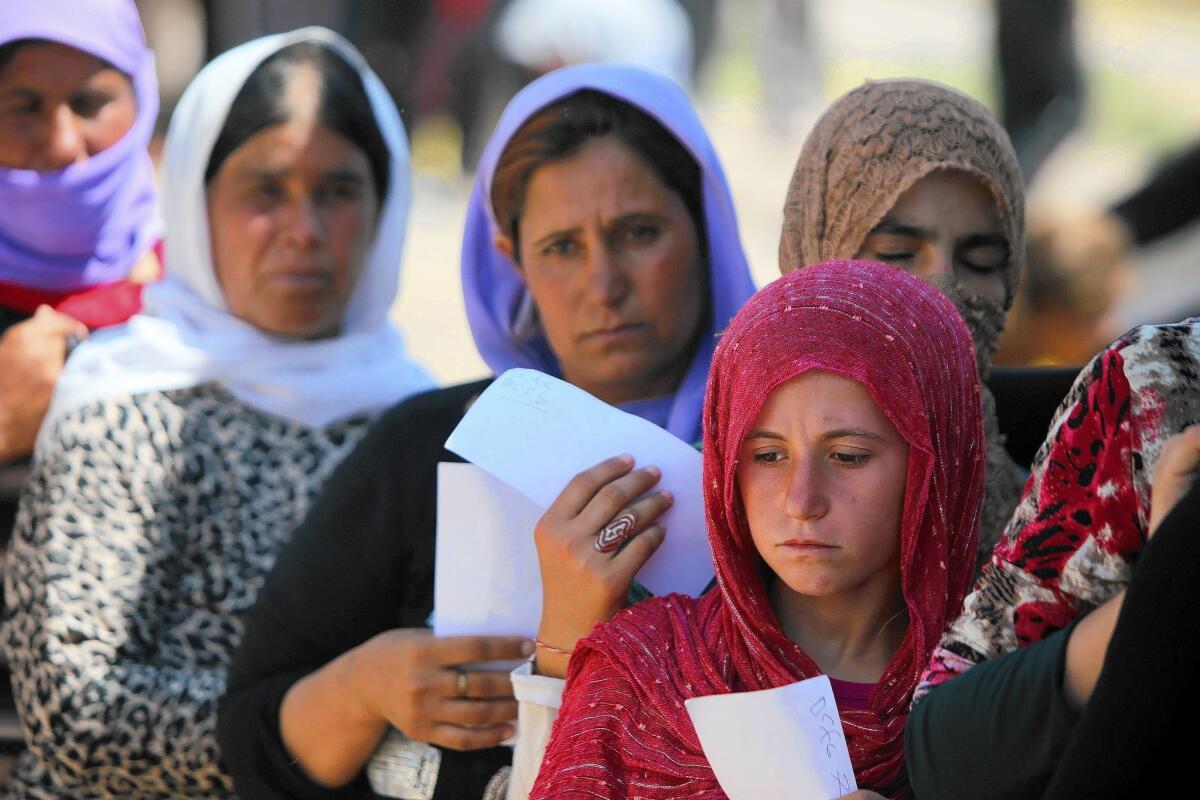 Yazidi women wait in line for food at a camp for the displaced in Iraqi Kurdistan's Dahuk province.