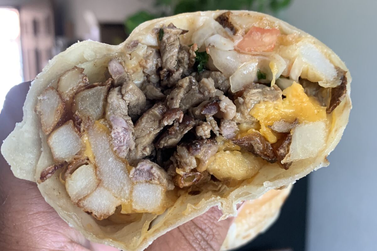 cross section of burrito showing fries, beef, cheese and pico de gallo