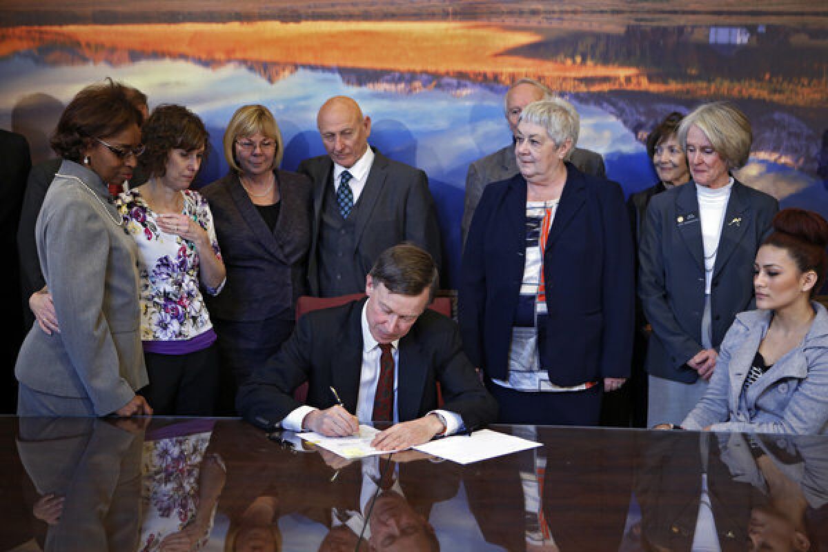 Sponsors and family members of victims watch Wednesday as Colorado Gov. John Hickenlooper signs gun-control bills into law at the Capitol in Denver.