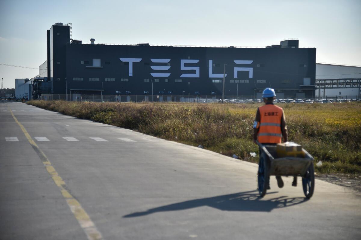 A worker walks on a road toward a Tesla factory.