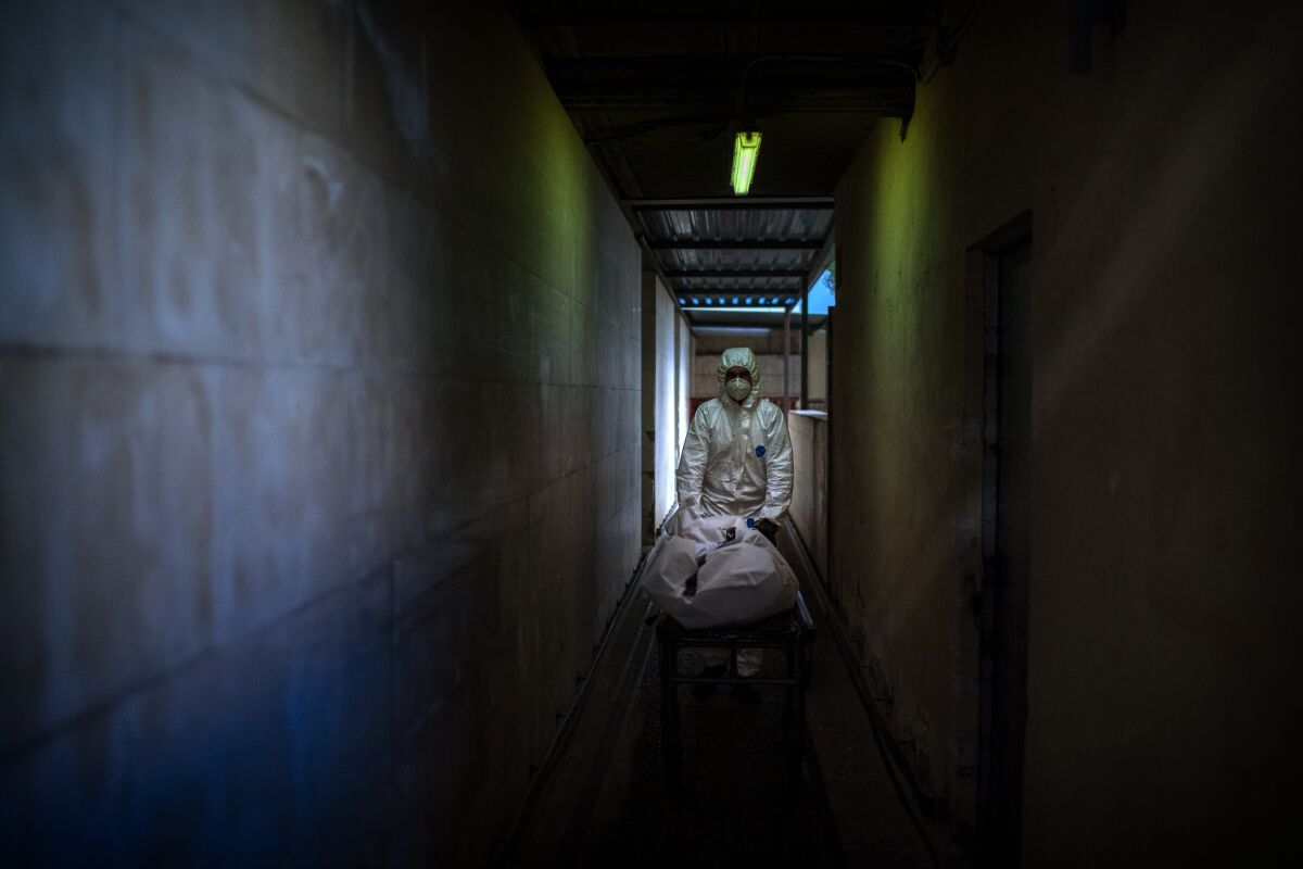 A mortuary worker transports the body of a person who died from COVID-19 from a hospital morgue in Barcelona, Spain.
