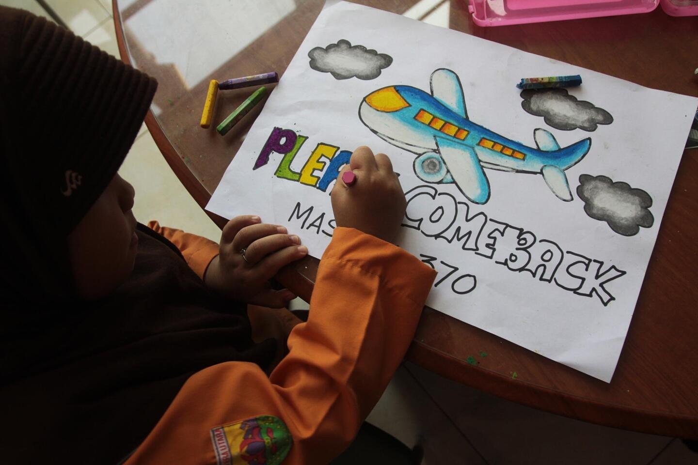 An Indonesian student writes a message expressing prayers and well-wishes for passengers onboard missing Malaysia Airlines (MAS) flight MH370 in Medan, North Sumatra, on March 15, 2014.