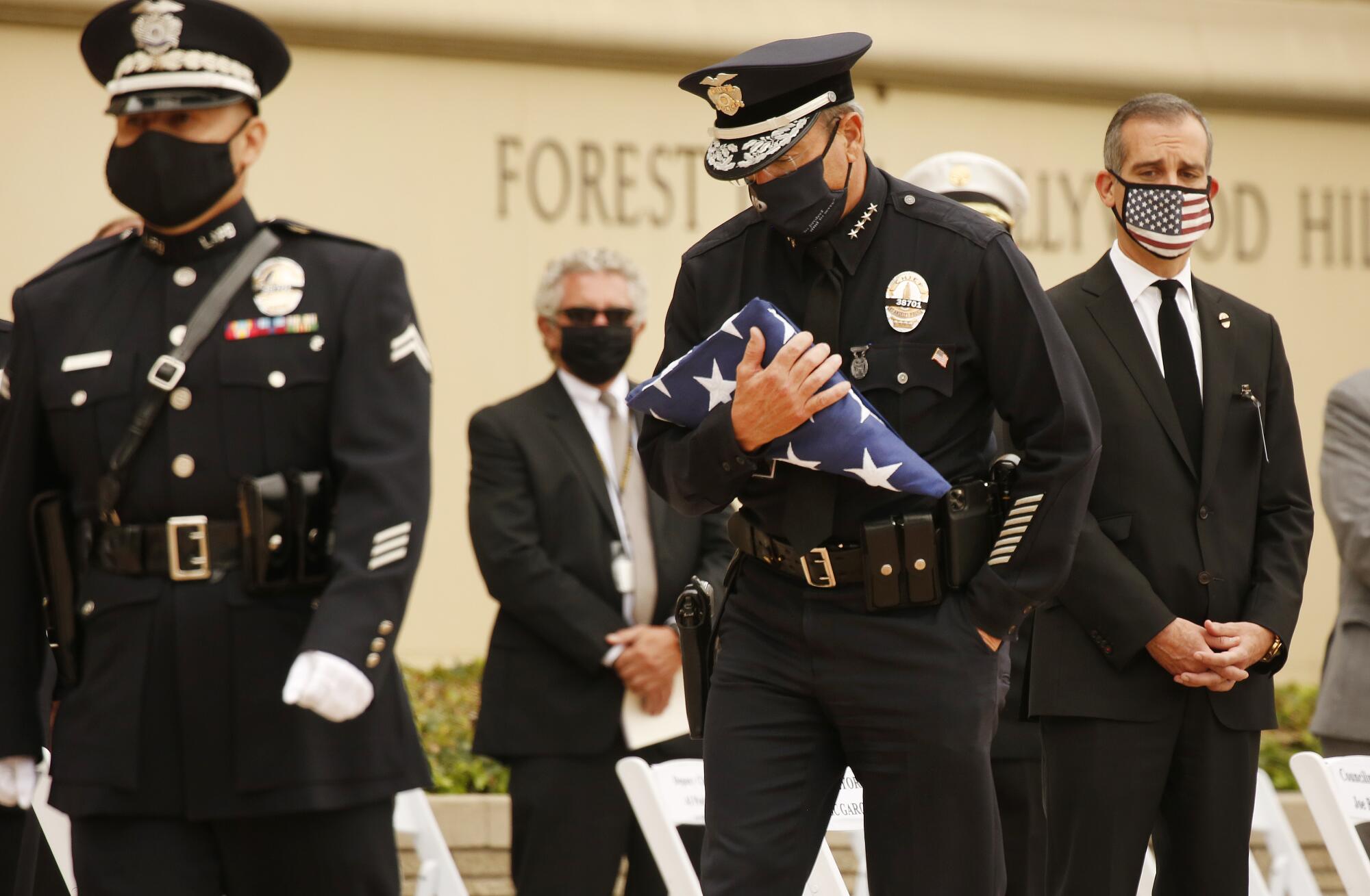 L.A. Police Chief Michel Moore holds the flag to present to Megan Flynn, Martinez's partner.  