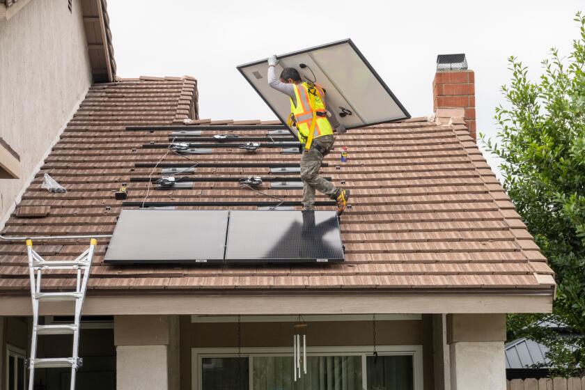 BREA, CA - JUNE 15: Solar Optimum installer Marat Poghosyan carries a solar panel into place at a house in Brea, CA on Thursday, June 15, 2023. (Myung J. Chun / Los Angeles Times)