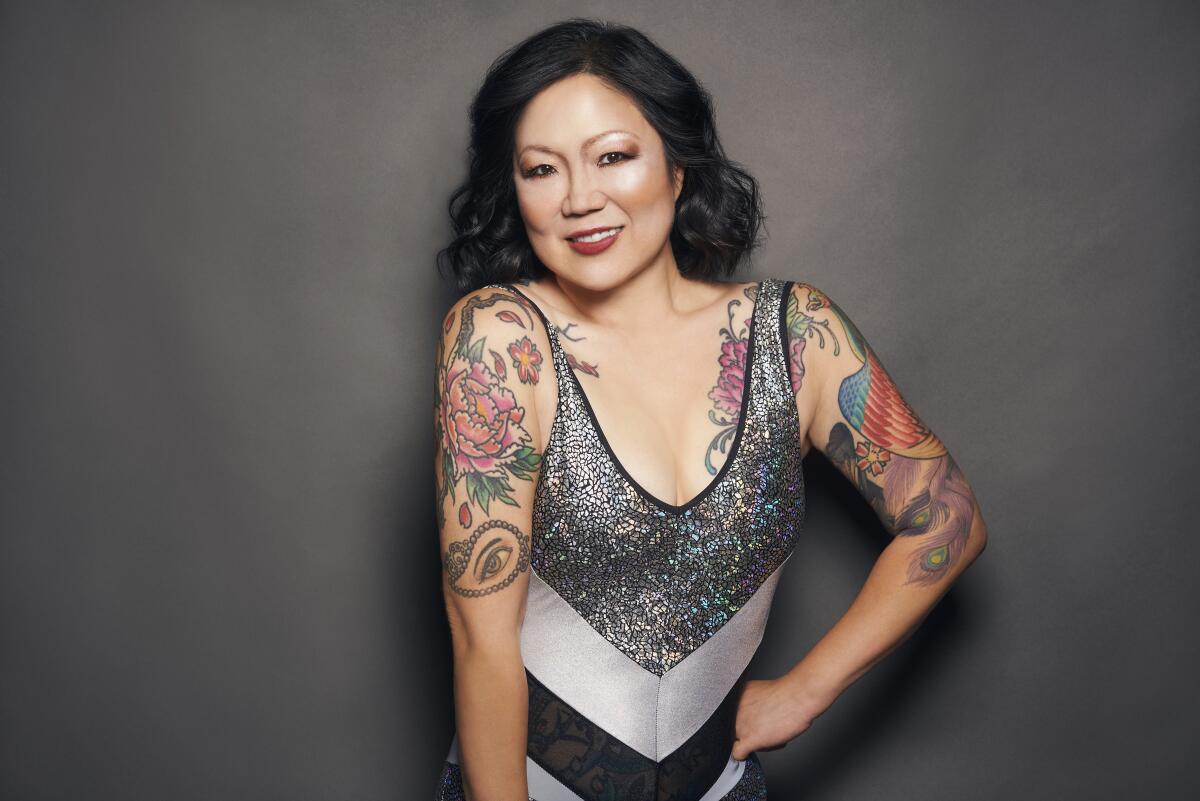 A woman in a tank top with tattoos on her shoulders and arms.