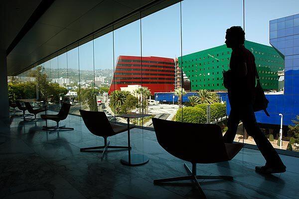 George Parr, 29, makes his way past chairs and floor-to-ceiling glass windows that look out onto the Pacific Design Center from the second-floor of the new West Hollywood Library. See full story
