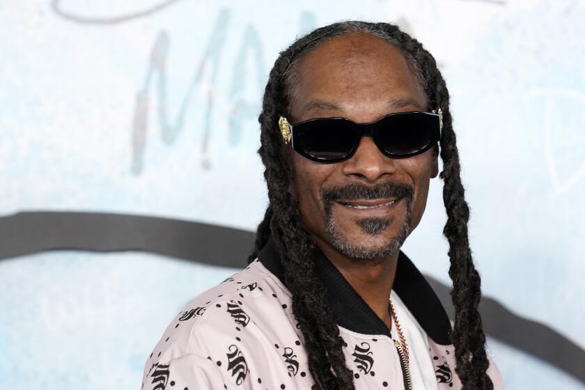 Snoop Dogg wears shades and smiles as he poses at the premiere of the FX docuseries "Dear Mama" 