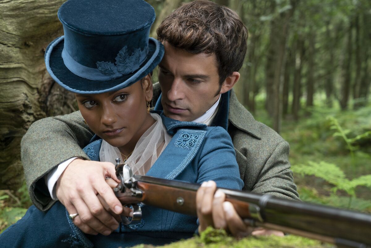 A man in period costume helps a woman aim her rifle 