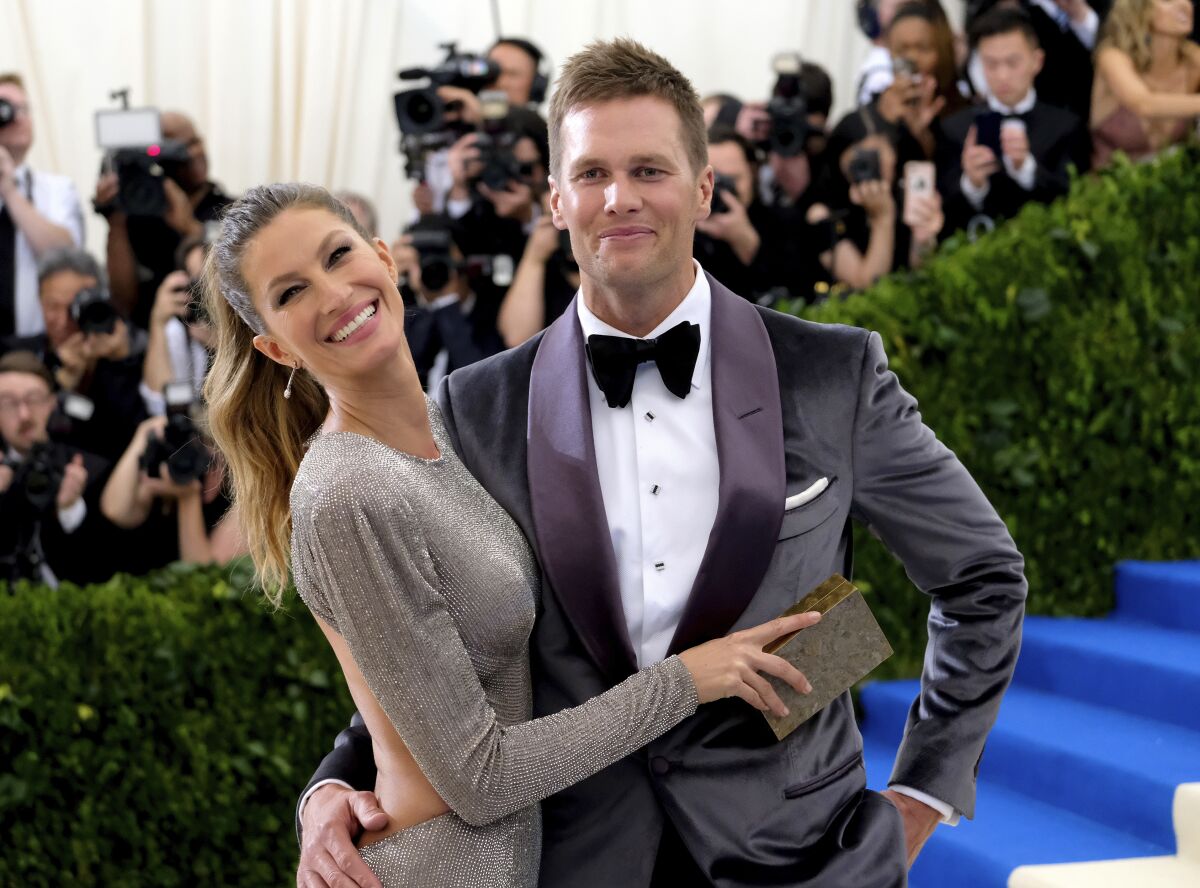 A model in a silver gown embracing a man in a velvet tuxedo and bow tie
