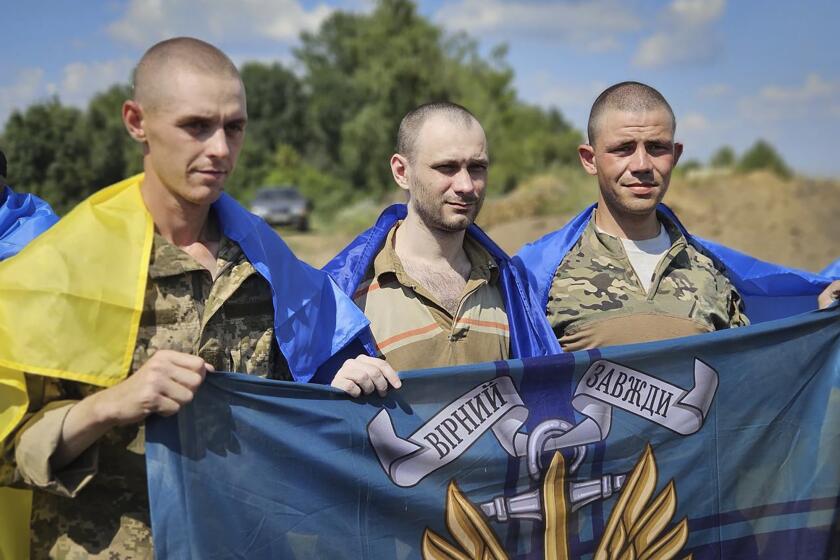 In this photo provided by the Ukrainian Presidential Press Office on Wednesday, July 17, 2024, Ukrainian prisoners of war hold Marine's flag as they pose for a photo after a prisoners exchange at an undisclosed location in Ukraine. (Ukrainian Presidential Press Office via AP)