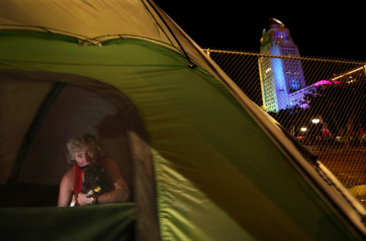 A woman sleeps on the sidewalk near Grand Park in downtown L.A. with her dog in 2019.