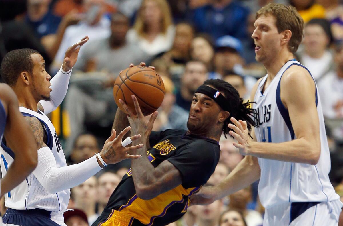 Lakes center Jordan Hill fights through the double-team defense of Mavericks forward Dirk Nowitzki, right, and guard Monta Ellis in the first half.