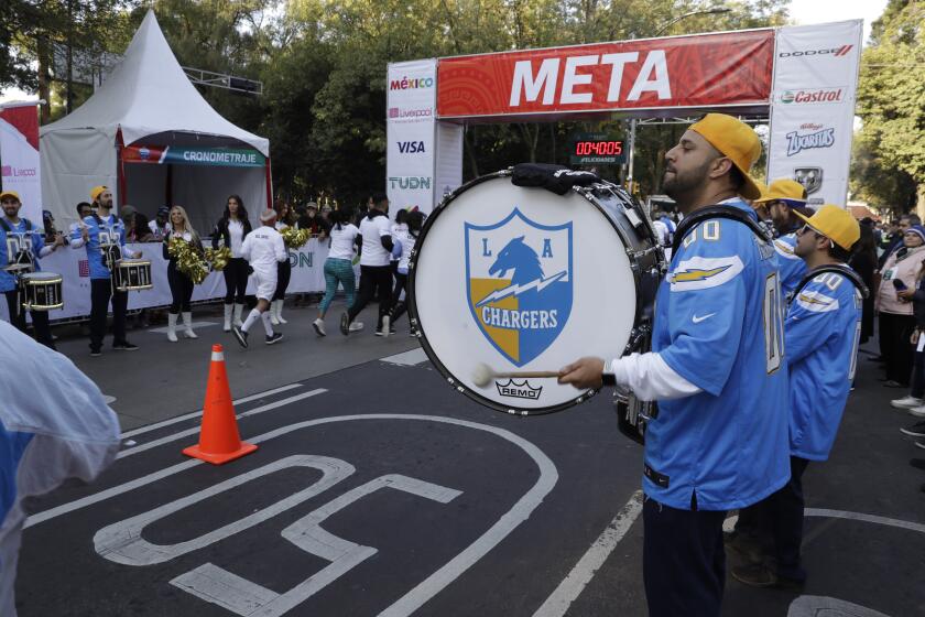 The Chargers' Thunderbolt Drumline and Lightning Crew greet runners at the finish line for a fan race in Mexico City on Nov. 17, 2019.