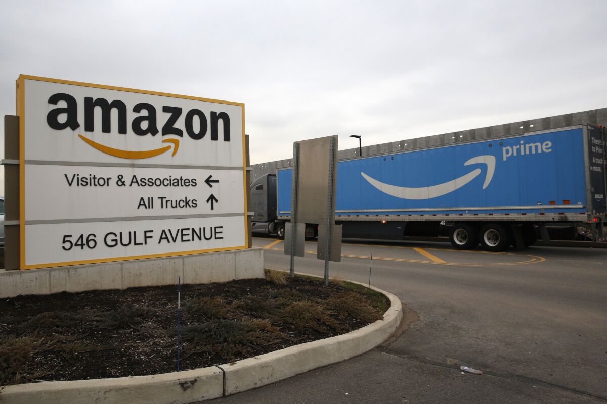 FILE - An Amazon Prime truck passes by a sign outside an Amazon fulfillment center March 19, 2020 in Staten Island, N.Y. The National Labor Relations Board has found merit to a complaint that Amazon violated labor law in New York City’s Staten Island by holding mandatory worker meetings to persuade its employees not to unionize. The agency’s determination was shared Friday, May 6, 2022 with an attorney representing the Amazon Labor Union, which filed the charge in the lead-up to the first successful U.S. organizing effort in the retail giant’s history. (AP Photo/Kathy Willens, File)