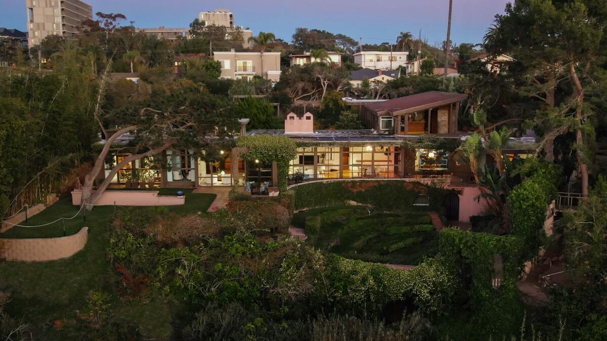 Aerial view of a sprawling home amid trees with walls of glass.