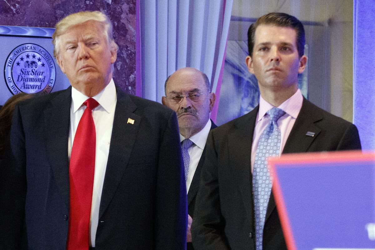 Allen Weisselberg stands behind Donald Trump and Donald Trump Jr. in the lobby of Trump Tower.