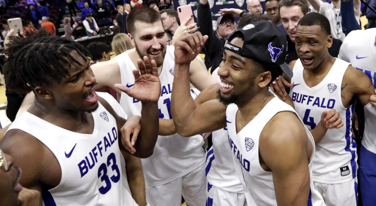 Buffalo's CJ Massinburg, right, and Nick Perkins, left, join teammates in celebrating their Mid-American Conference championship game victory.