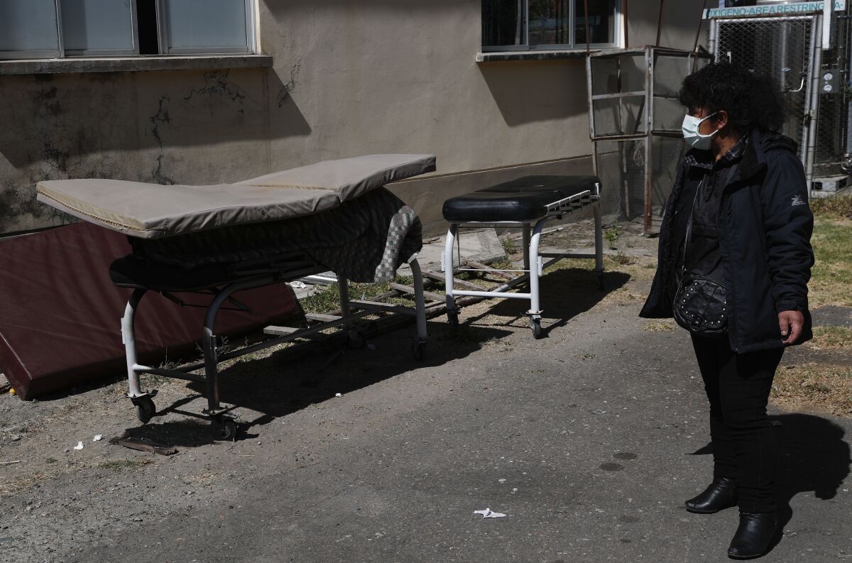 Herminia Carpio looks at the body of her brother Guillermo, covered by a slim mattress, outside a hospital in Bolivia.
