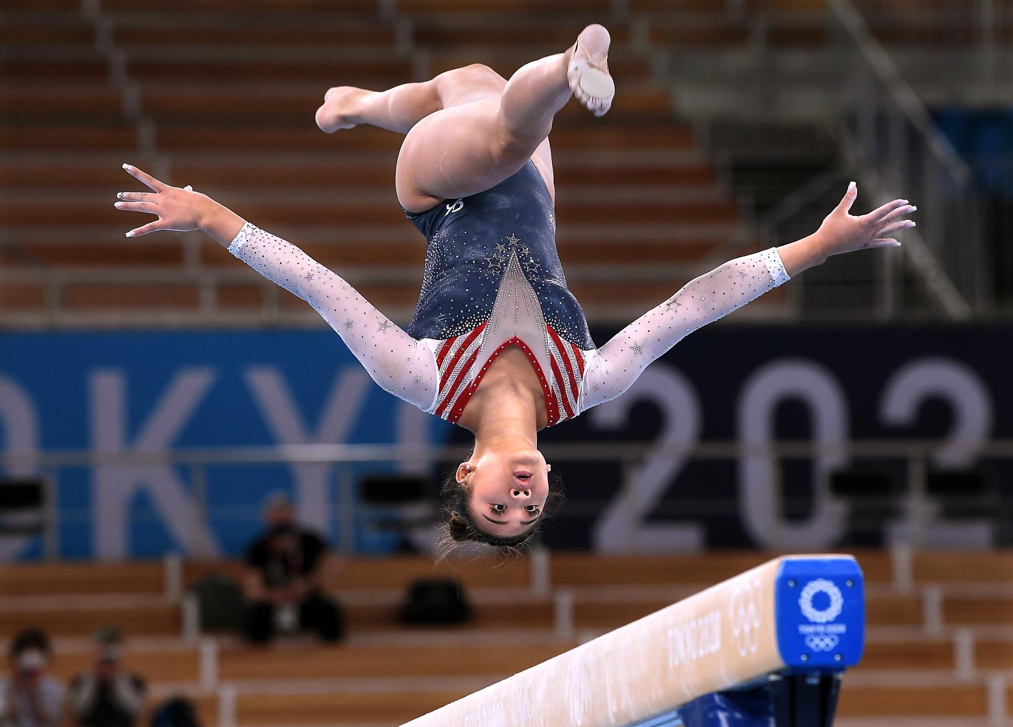 Team USA's Suni Lee upside-down in the air above the beam
