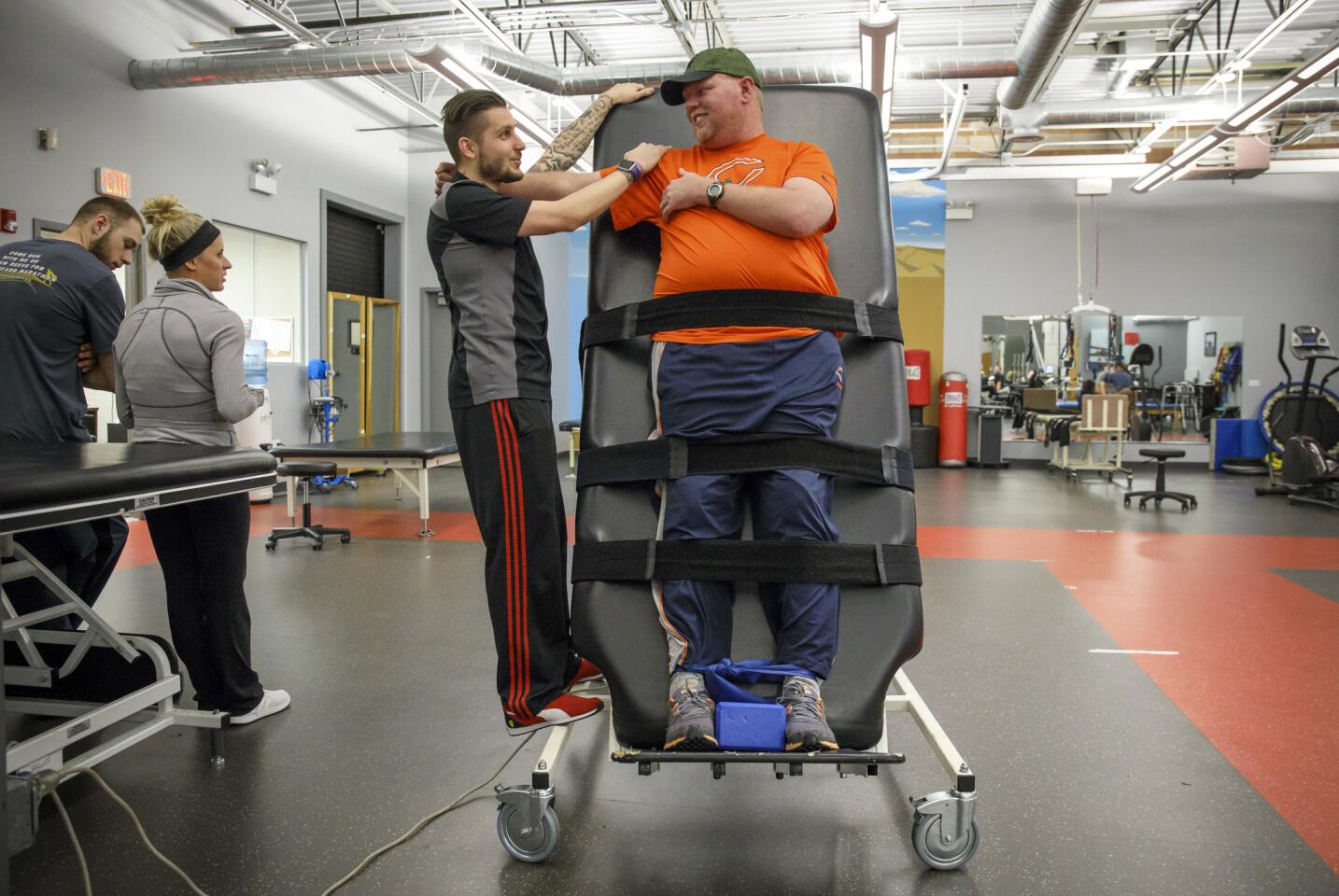 Michael LaPorta stretches with the assistance of neurofitness specialist Creighton Goss during a physical therapy session on March 20, 2017, at the Next Steps rehabilitation center.