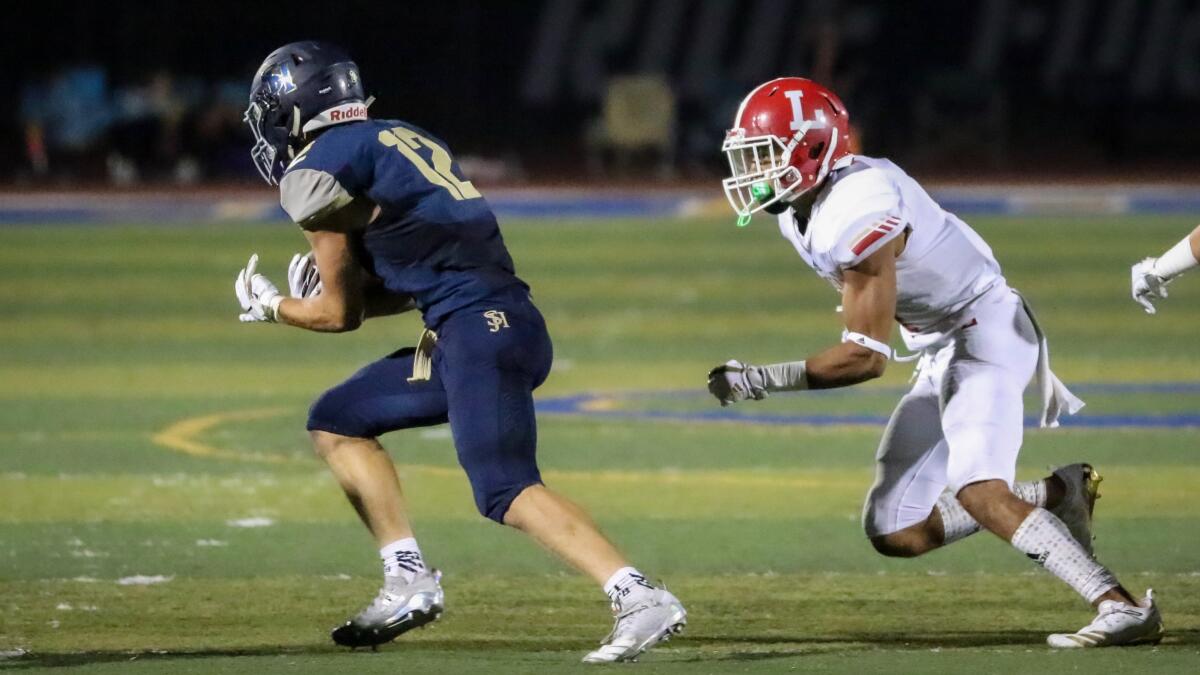 San Juan Hills receiver Joey Hobert (12) evades an Orange Lutheran defender after short catch in a game on Aug. 17, 2018.