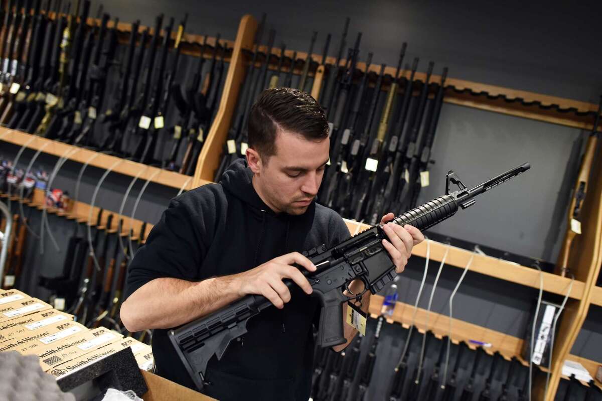 An employee checks the chamber of an assault-style rifle at a shooting range in Randolph, N.J. on Dec. 9.