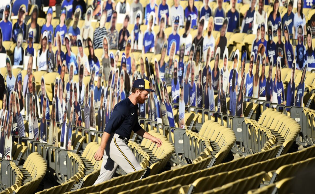 Milwaukee Brewers pitcher Brandon Woodruff walks past fan cutouts in the Dodger Stadium seats on Tuesday.