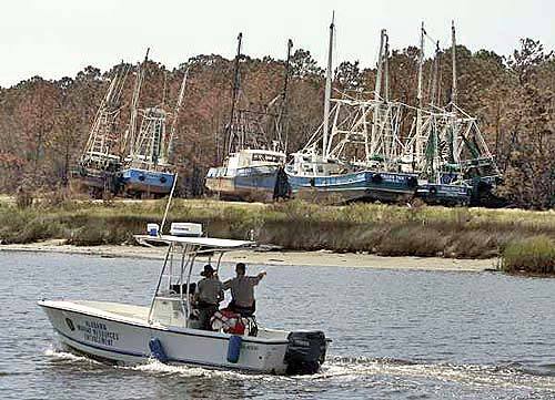Alabama Marine Resources Enforcement officers look over boats that were grounded by Hurricane Katrina in Bayou La Batre, Ala. The storm took 85-foot fishing vessels and tossed them ashore.